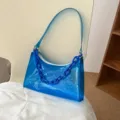 Trendy blue transparent PVC jelly shoulder bag with resin chain detail on chair. - 24*6*17CM / Blue