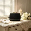 Elegant black hexagonal clutch bag with crocodile texture on white lace table. - Black