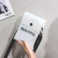 Hand holding a trendy white transparent PVC jelly bag with black BEAUTIFUL letter print - 13x18x5cm / White