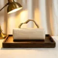 Detail view of retro crocodile pattern clutch with unique wavy gold handle on a tray. - Off White