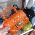 Detailed close-up view of a bright orange transparent jelly bag with a beaded handle - Transparent Orange