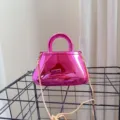 Close-up view of a metallic pink acrylic evening box bag featuring a gold chain strap - Pink