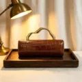 Elegant brown crocodile pattern PU evening clutch bag featuring a gold sculptural handle - Tan