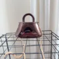 Dettaglio della borsa da sera in acrilico riflettente con elegante catena dorata - Nero