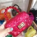 Detailed view of a bright pink mini quilted jelly bag with a stylish red bead handle - Translucent Red