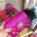 Detail of a pink quilted jelly bag featuring a gold twist lock and stylish beaded handle - Translucent Rose Red