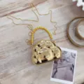 Gros plan d'un mini sac de soirée doré en forme de nuage avec une poignée perlée - Or clair