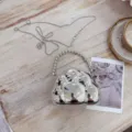 Gros plan d'un mini sac de soirée argenté en forme de nuage avec anse perle sur bois - Argent