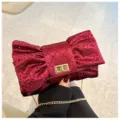 Détail d'une pochette de soirée bordeaux en forme de nœud avec strass et chaîne d'or. - Rouge