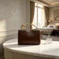Detailed view of the creative golden rose handle on a luxurious brown evening clutch. - Dark Brown