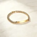 Detailaufnahme des goldpolierten Edelstahl-ID-Armbands mit Panzerketten-Gliedern - Herrenstil / Gold