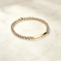 Detailansicht eines vergoldeten Edelstahl-Panzerarmbands mit ID-Platte auf Marmor - Damenstil / Gold
