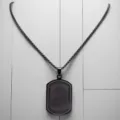 Macro detail of black stainless steel dog tag pendant with engraved border pattern - Black Arabic Plate - Pearl Chain