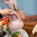 Gros plan d'un sac à main en PVC plissé rose en forme de citrouille sur fond floral. - 14.5*7.5*10cm / Abricot