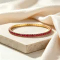 Close-up detail of a high-end gold-toned stainless steel elastic bracelet with red zircon - Red Zirconia Bracelet / Red