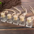 Closeup of empty glass car perfume bottles with wooden caps and hanging ropes for essential oils. - Square Bottle