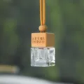 Dettaglio della bottiglia diffusore di oli essenziali sospesa per auto con tappo in legno. - Con Testo Inglese / Beige