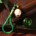 Detailansicht eines Autoparfümanhängers mit gravierter Holzkappe und grüner Glasflasche - Grün