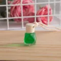 Dettaglio flacone profumo per auto appeso, diffusore verde con tappo in legno e corda. - Gelsomino verde