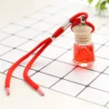 Car perfume pendant detail showing red liquid bottle with wooden cap and hanging rope. - Osmanthus