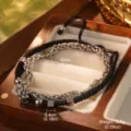 Detalle de una pulsera de acero de titanio de doble capa con cuerda trenzada negra y cubos. - 40CM
