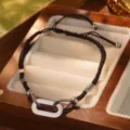 Primer plano de pulsera trenzada negra de acero de titanio con eslabones plateados - Talla única/Ajustable