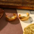 Close-up of vintage gold C-shaped earrings with an elegant ribbed texture detail - Glossy Gold
