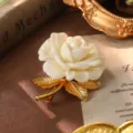 Detailed view of a vintage white rose brooch with textured gold leaves on a classic background - Ivory White Rose Brooch (BR1-2596-6800)
