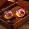 Gros plan de boucles d'oreilles émaillées vintage avec fleur rose et détails en perle. - Style Peinture à l'Huile Fleur Rose (26779A)