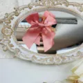Detailed close-up of a pink satin bow hair claw clip displayed on an ornate vintage mirror tray - Korean Pink