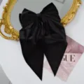 Macro view of black velvet hair clip showing large bow design with elegant long streamers - Black