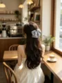 Detailed view of a grey polka dot bow hair claw clip styled on long wavy hair - Blue Gray