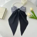 Detail view of large black gingham satin hair bow with long streamers on white plate - Black Small Plaid