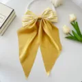 Close-up detail of yellow checkered fabric and satin streamer bow hair clip on white surface - Yellow Plaid