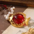 Detailed macro view of vintage gold fish brooch with red gem and pearl accents - Vintage Red Stone Fish Shape Style (BR1-2563A-7000)