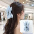 Detailed view of a light blue fabric bow hair claw clip worn on long brown hair - Light Blue