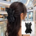 Large black fabric bow hair claw clip shown on a woman's hair with product close-up - Black