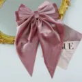 Close-up detail of a vintage dusty rose velvet bow hair clip with long elegant streamers - Pink