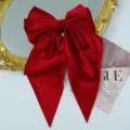 Macro view of a vintage red velvet bow hair clip with long streamers and texture detail - Red