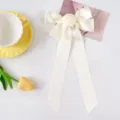 Detail of handmade cream satin ribbon bow hair clip with a central fabric rose accent. - Off White