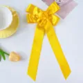 Close-up of bright yellow ribbon bow hair clip with handmade rose and long streamers. - Yellow