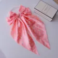 Macro detail view of a large pink polka dot satin bow hair clip with long elegant ribbons - Pink Polka Dot