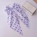 Polka dot bow hair clip with streamers presented elegantly beside a branded gift box. - White Polka Dot