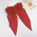 Detailed close-up of a large red chiffon bow hair clip with elegant long streamers. - Red