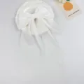 Close-up detail of an elegant white chiffon bow hair clip with long flowing ribbons - White
