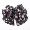 Detail view showing the delicate floral print on a black chiffon bow hair claw - Floral Sea Print
