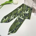Detail view of a green botanical print silk ribbon hairband on white background. - Green Botanical Ribbon