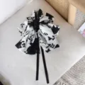 Detail shot of a vintage black and white floral print bow hair claw clip on a chair. - White Black Floral