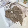 Close-up detail of a vintage houndstooth bow hair clip featuring elegant pearl accents - White and Brown Houndstooth