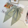 Primer plano de un pasador de pelo con lazo floral azul y cintas largas elegantes - Verde